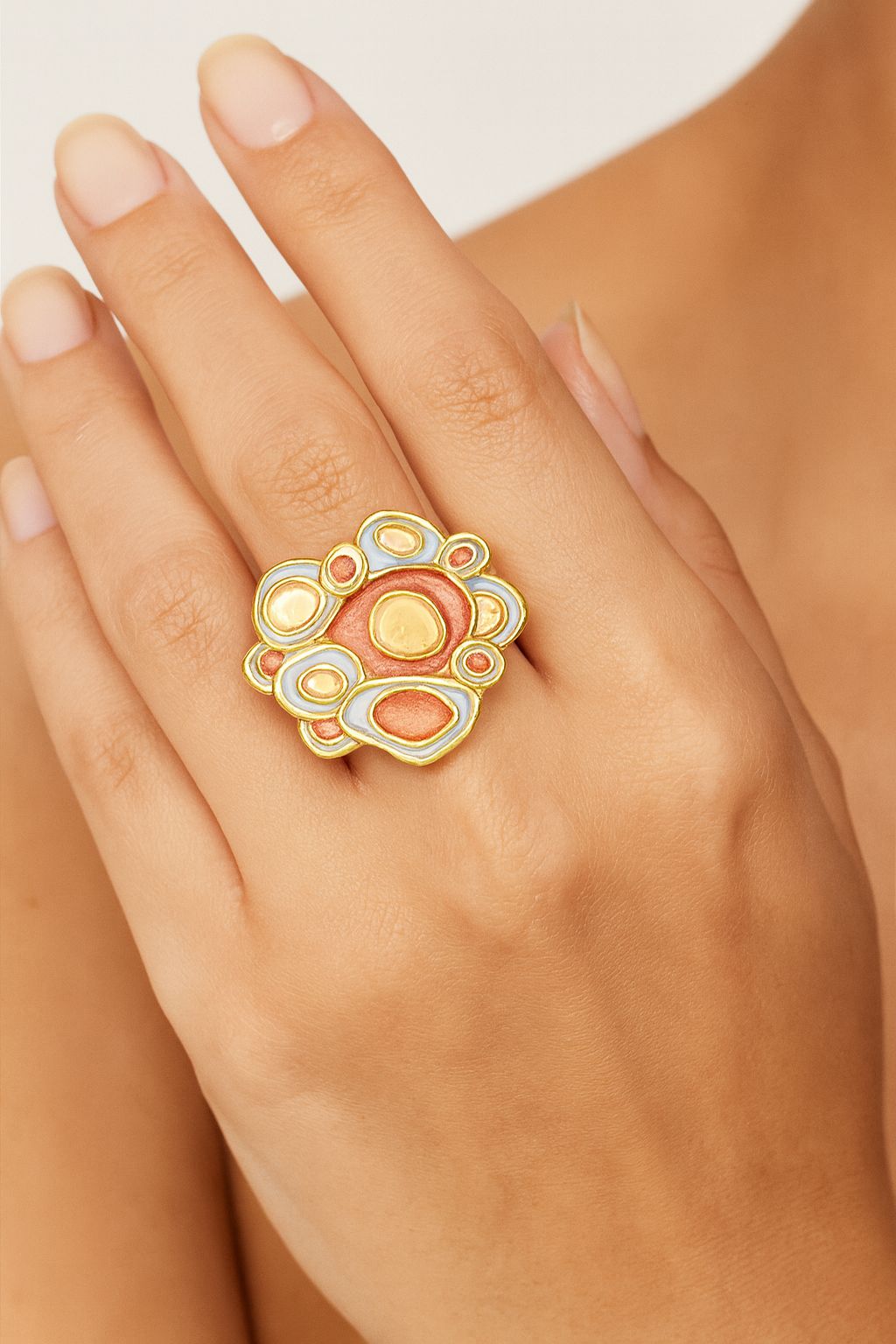 Close-up view of artistic KC gold enamel ring on hand