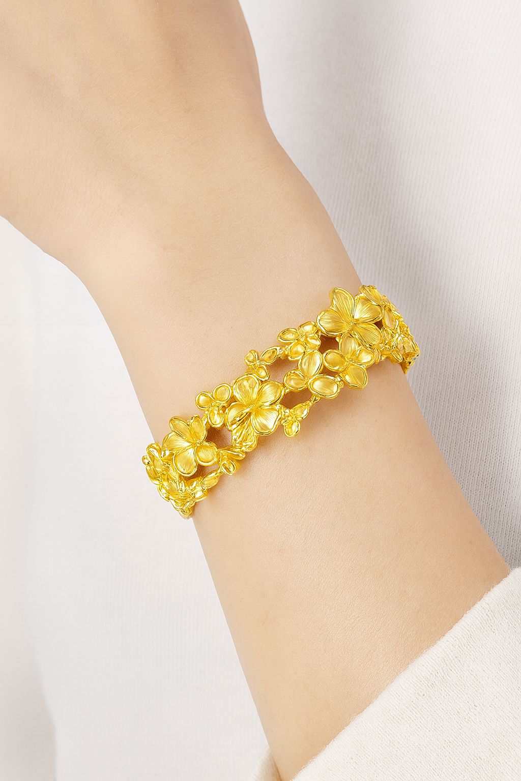 “Model wearing gold floral bracelet with artistic enamel detailing”