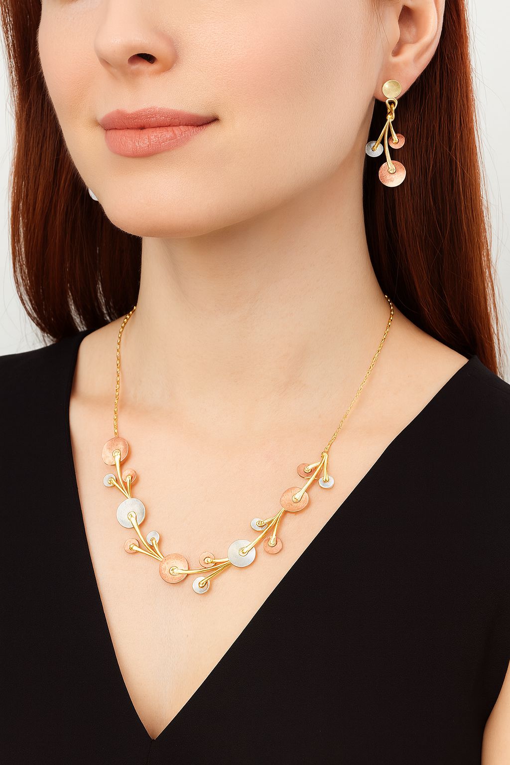 Model wearing gold enamel statement necklace and matching earrings