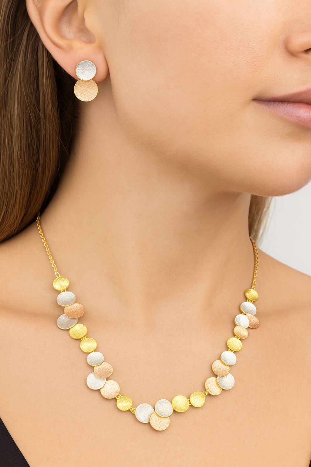 “Model wearing tri-tone disc necklace and earrings set with artistic enamel details”