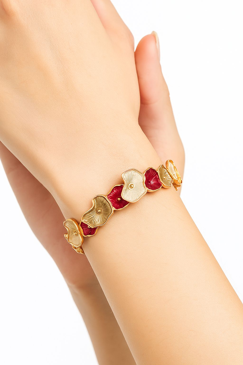 Model wearing gold floral bangle bracelet with red and champagne enamel petals