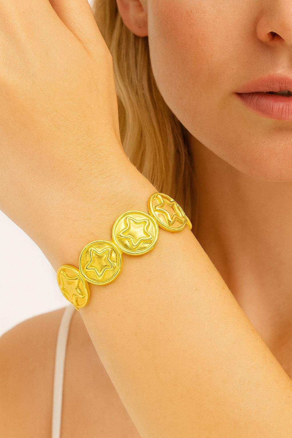Star embossed gold bracelet with KC gold plating and stretch link design on woman's wrist