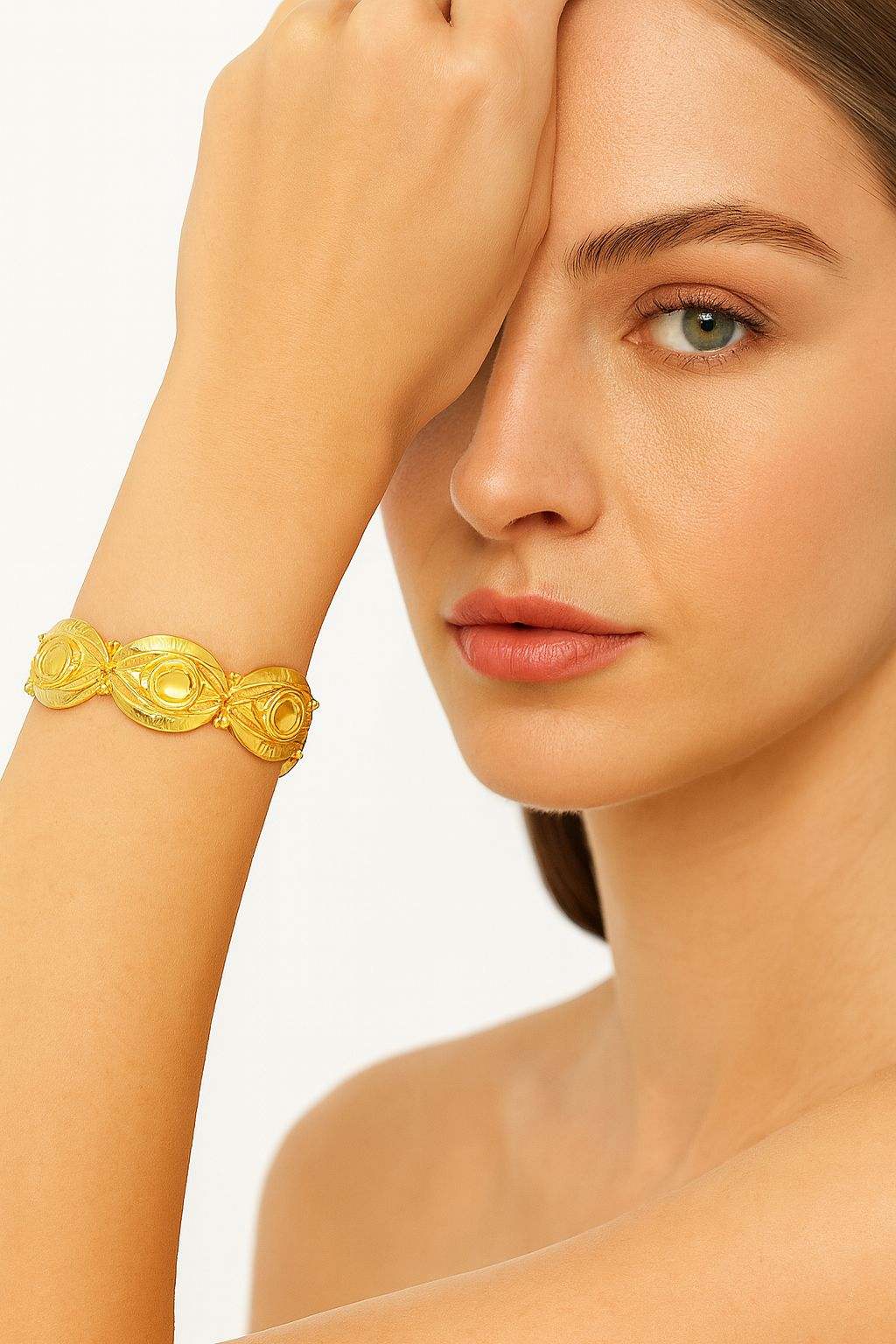 Artistic gold bangle featuring sculpted oval patterns and thin-film painting