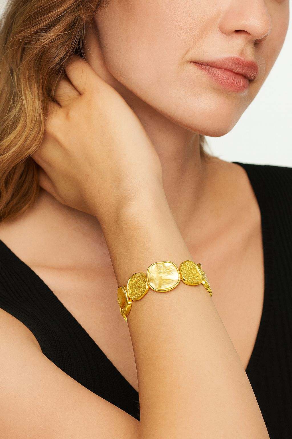 Woman wearing a vintage textured coin bracelet with KC gold plating and hand-painted detailing