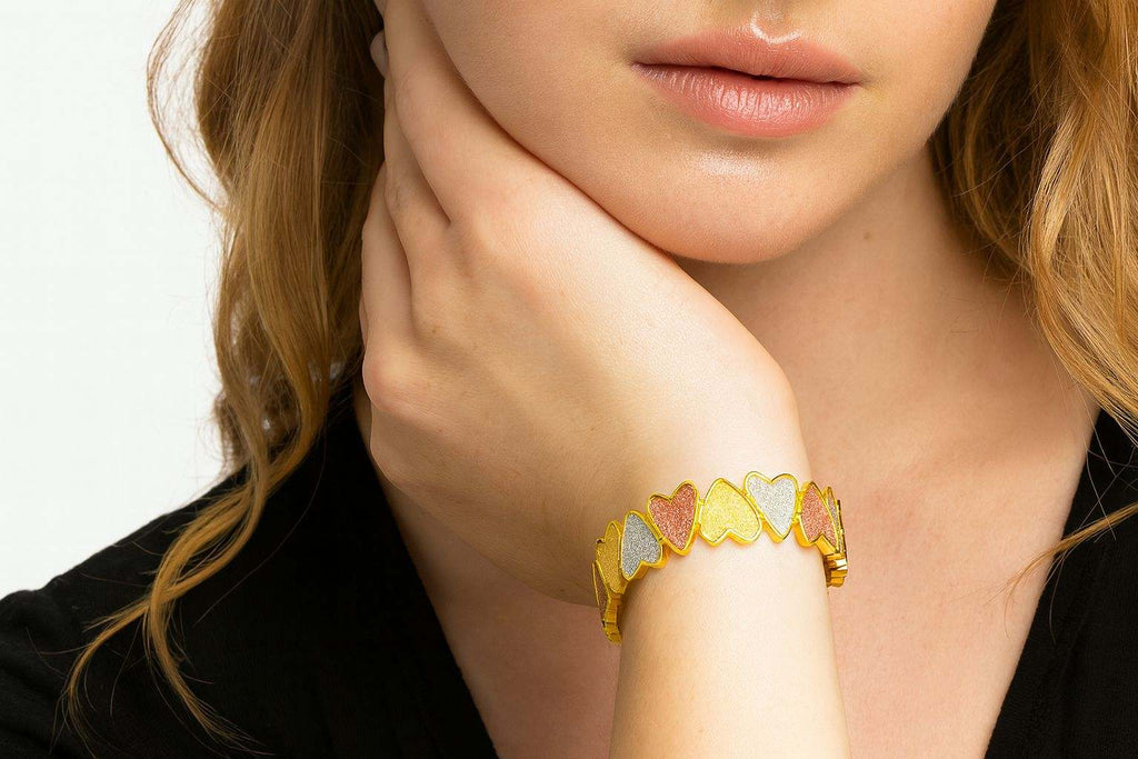 KC gold plated tri-color heart link bracelet with hand-painted glitter texture on woman's wrist