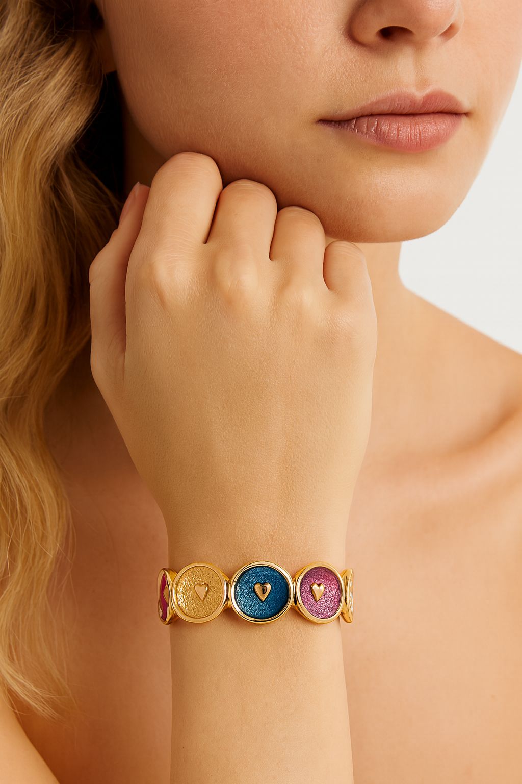 Model wearing colorful heart enamel gold bracelet in blue and pink tones