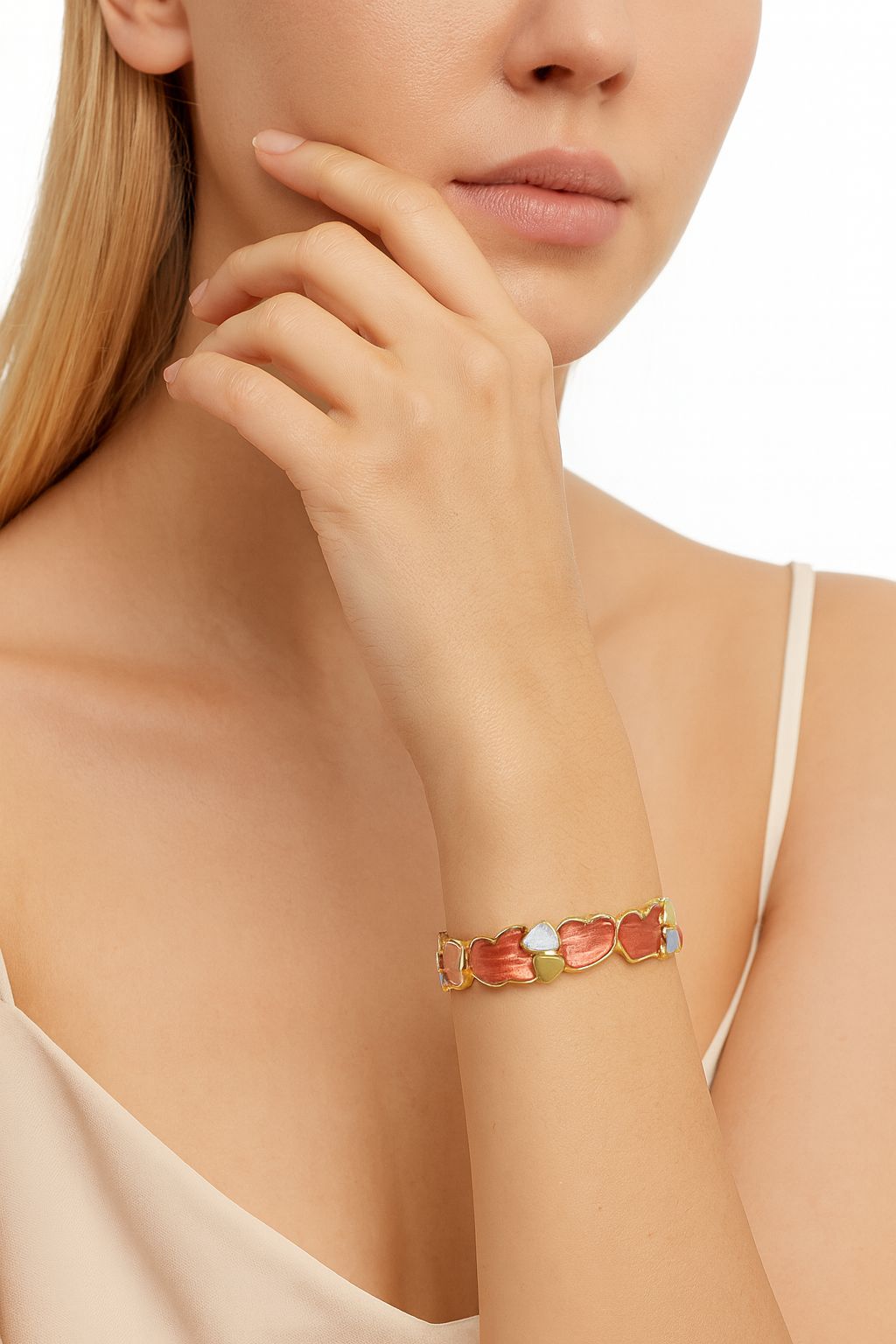 Heart enamel bracelet worn on wrist in gold, coral, and silver color tones