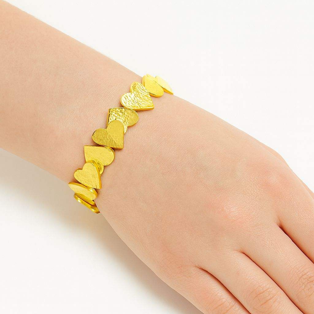 Close-up of a textured heart gold bracelet with layered heart charms on a wrist, showcasing a hand-painted KC gold plated finish and adjustable fit.