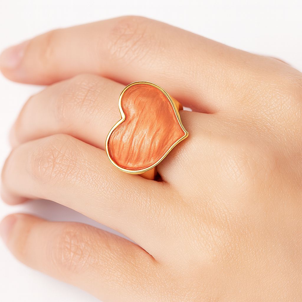 Model wearing coral enamel heart ring on hand