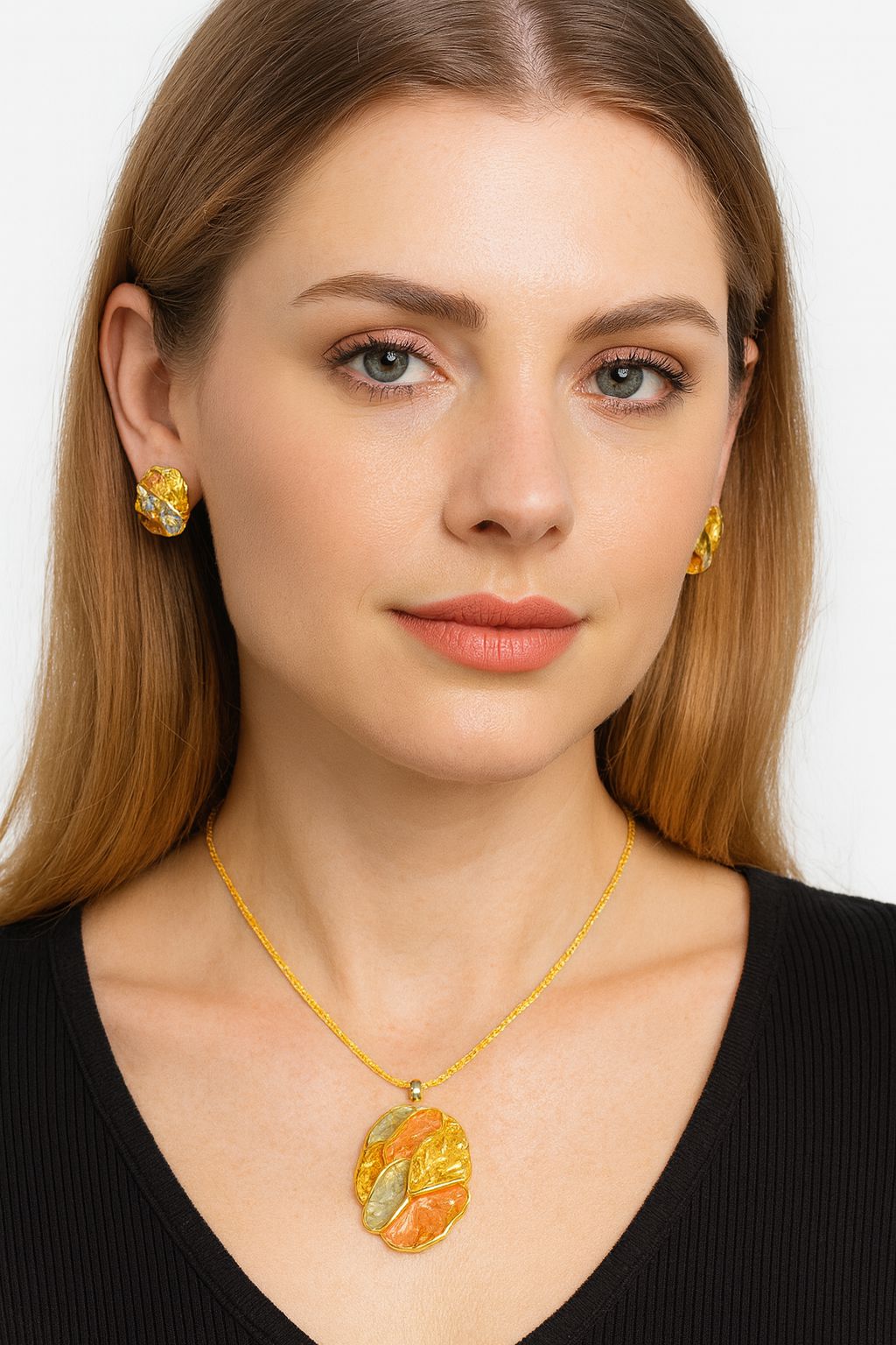 Model wearing artistic multi-tone pendant necklace and earrings