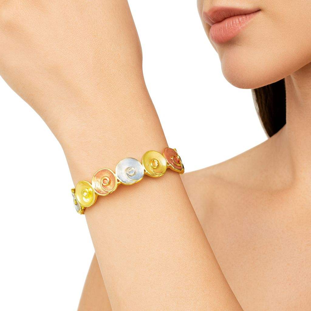Woman wearing tri-color spiral disc bracelet with gold, silver, and rose-gold swirl design