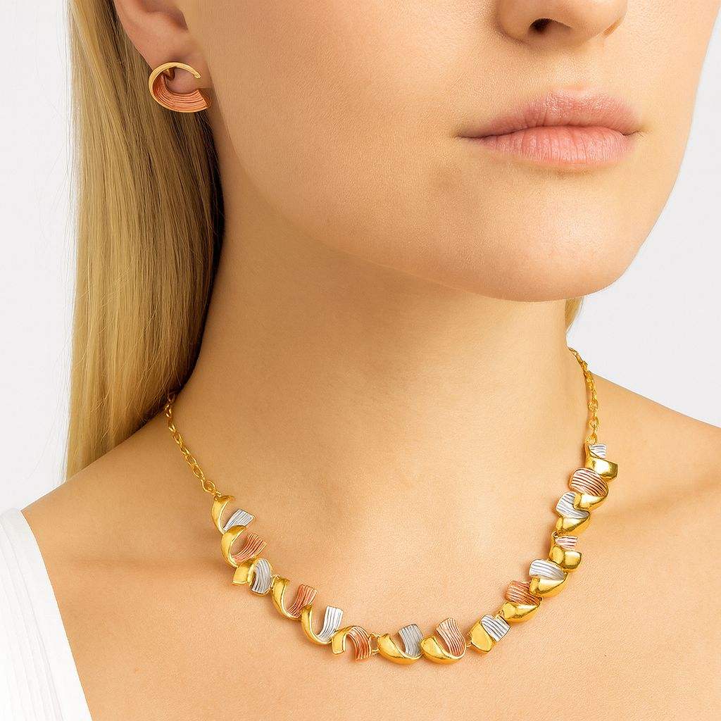 Modern gold necklace set with tricolor wave design and matching earrings worn by woman