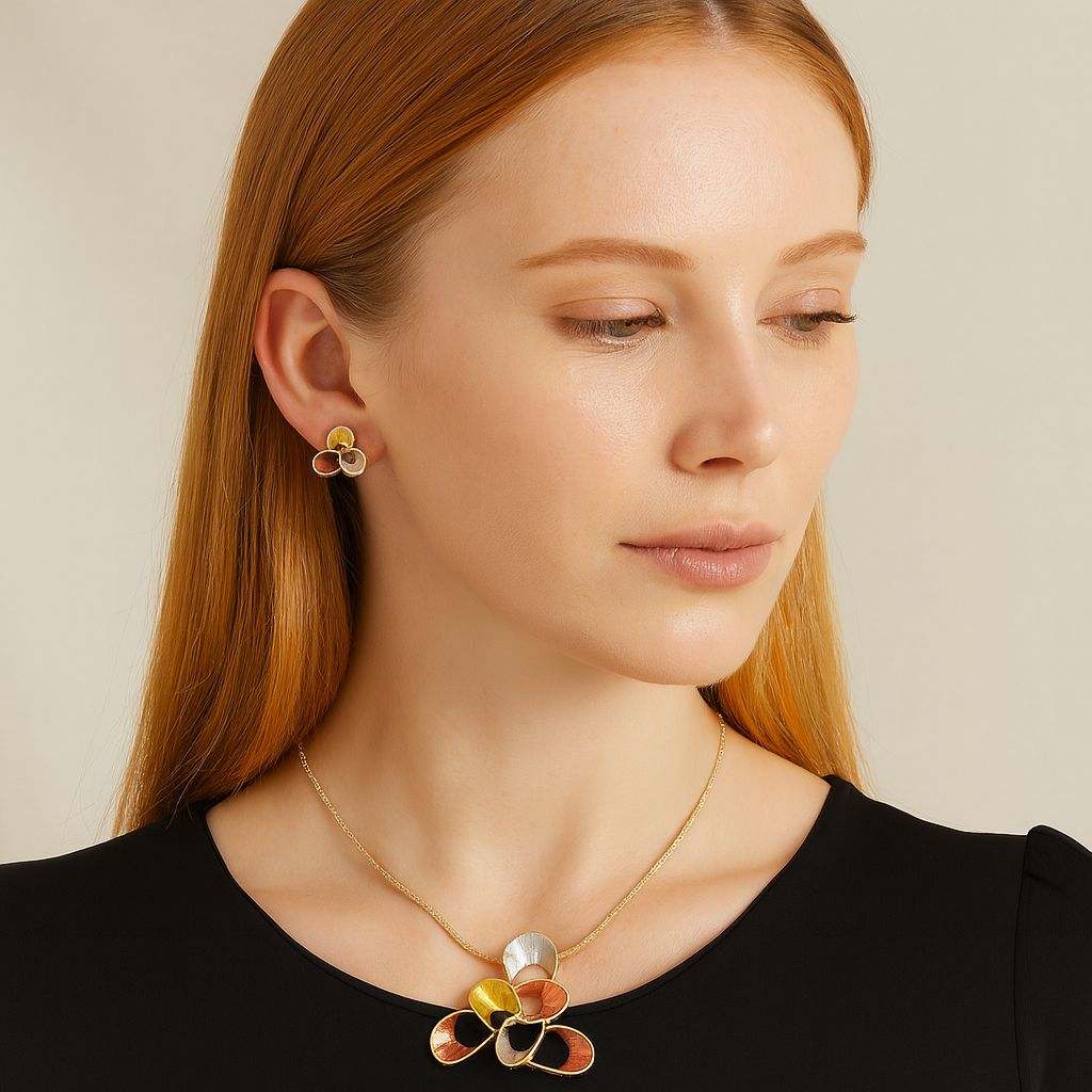 Elegant gold pendant necklace with geometric tricolor floral design and matching stud earrings on woman with red hair