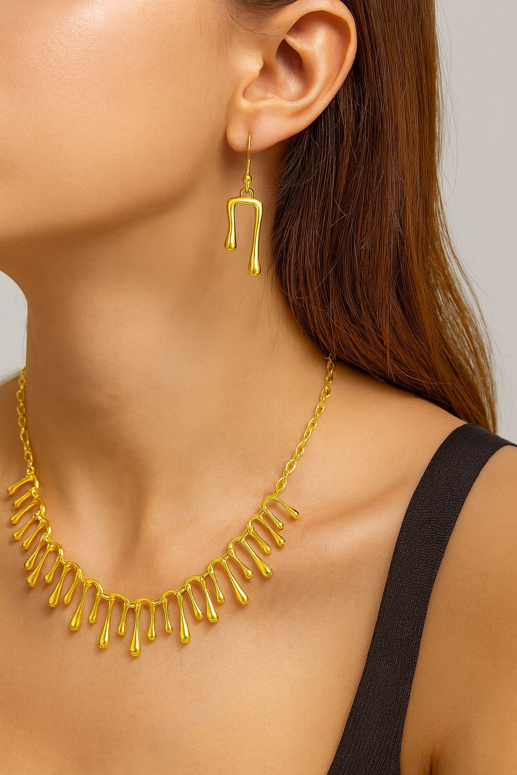 Model wearing gold drip necklace and matching earrings