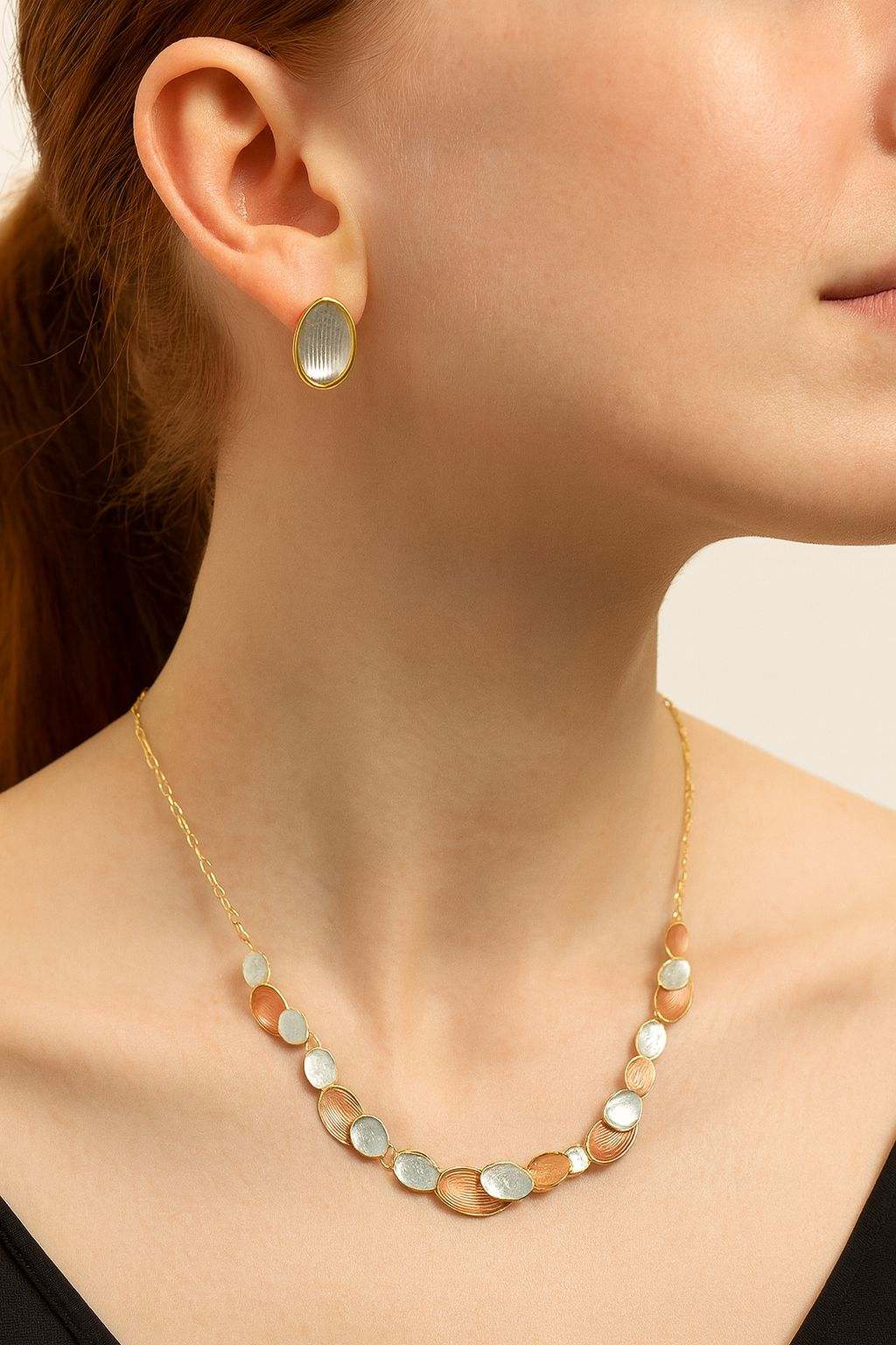 Woman wearing gold oval necklace and matching multi-tone oval earrings set