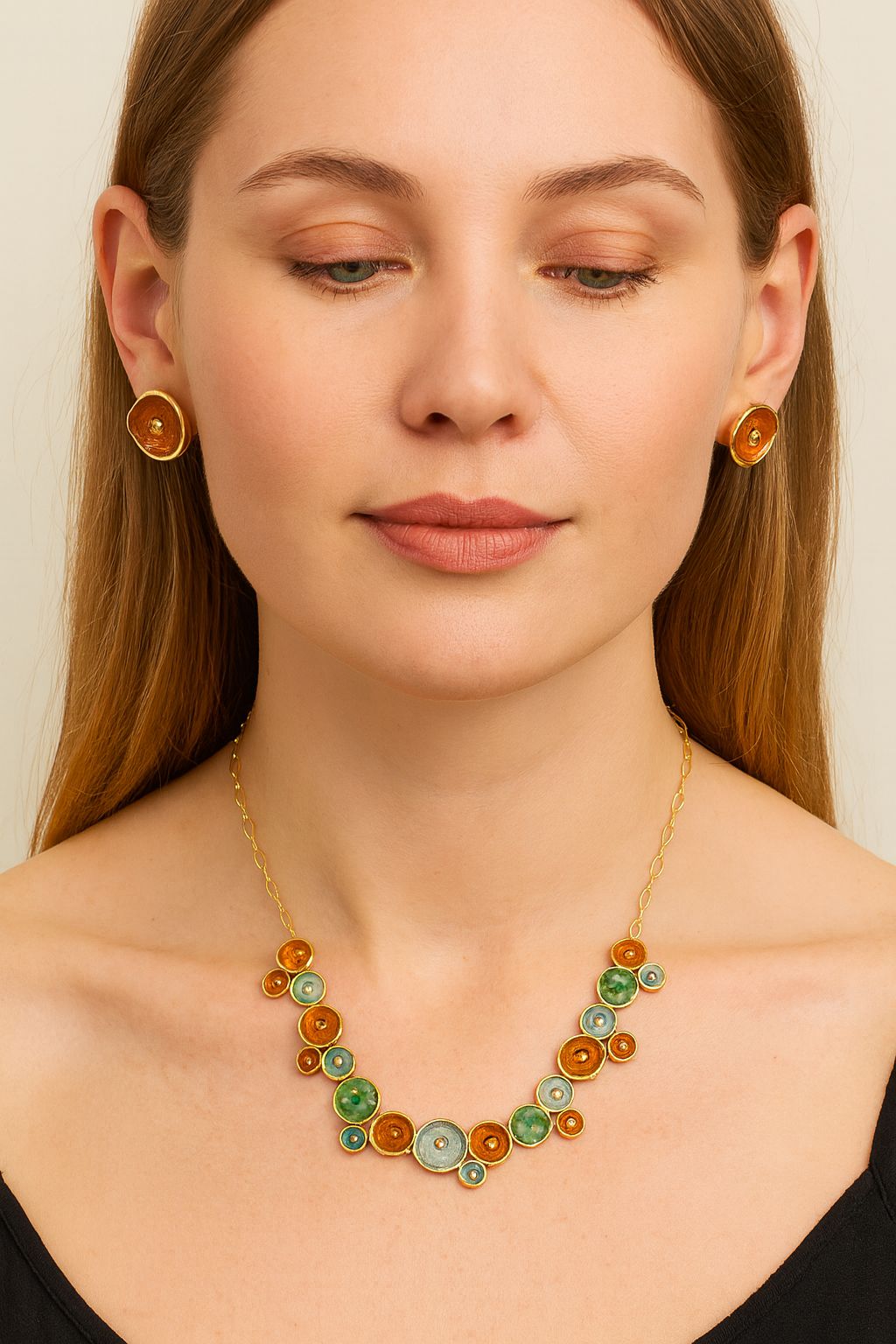 Model wearing artistic circle necklace and earrings in green and amber tones