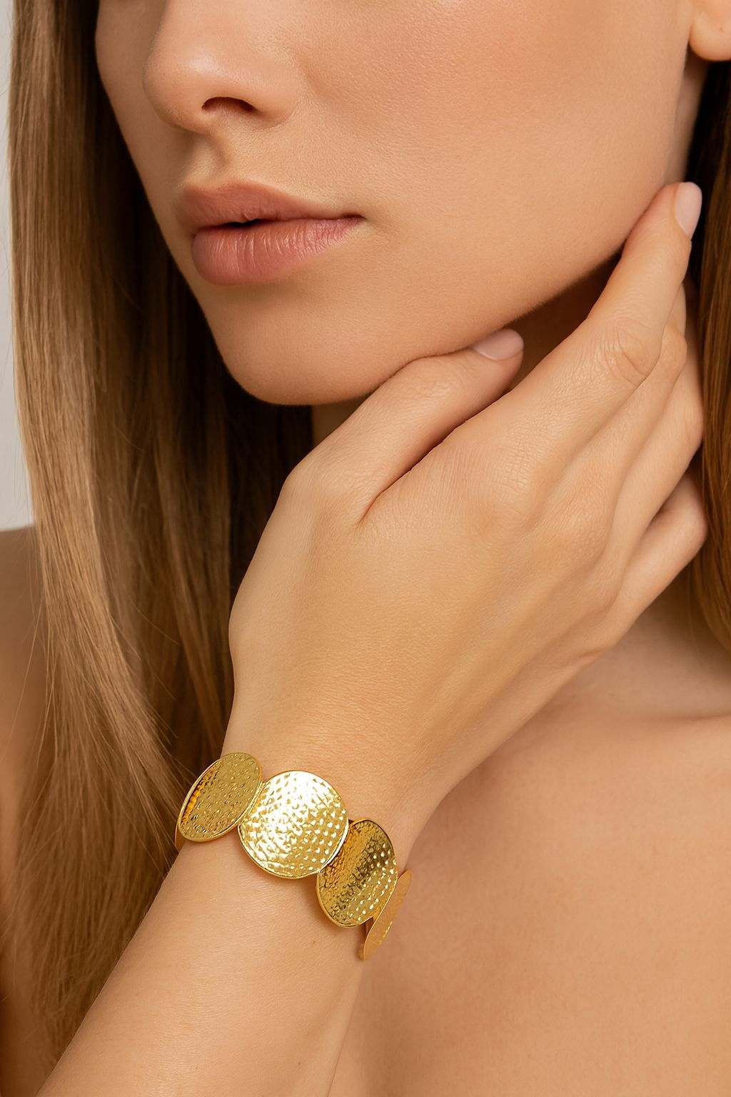 Woman wearing hammered disc KC gold plated bracelet by Pallas Jewellery on wrist