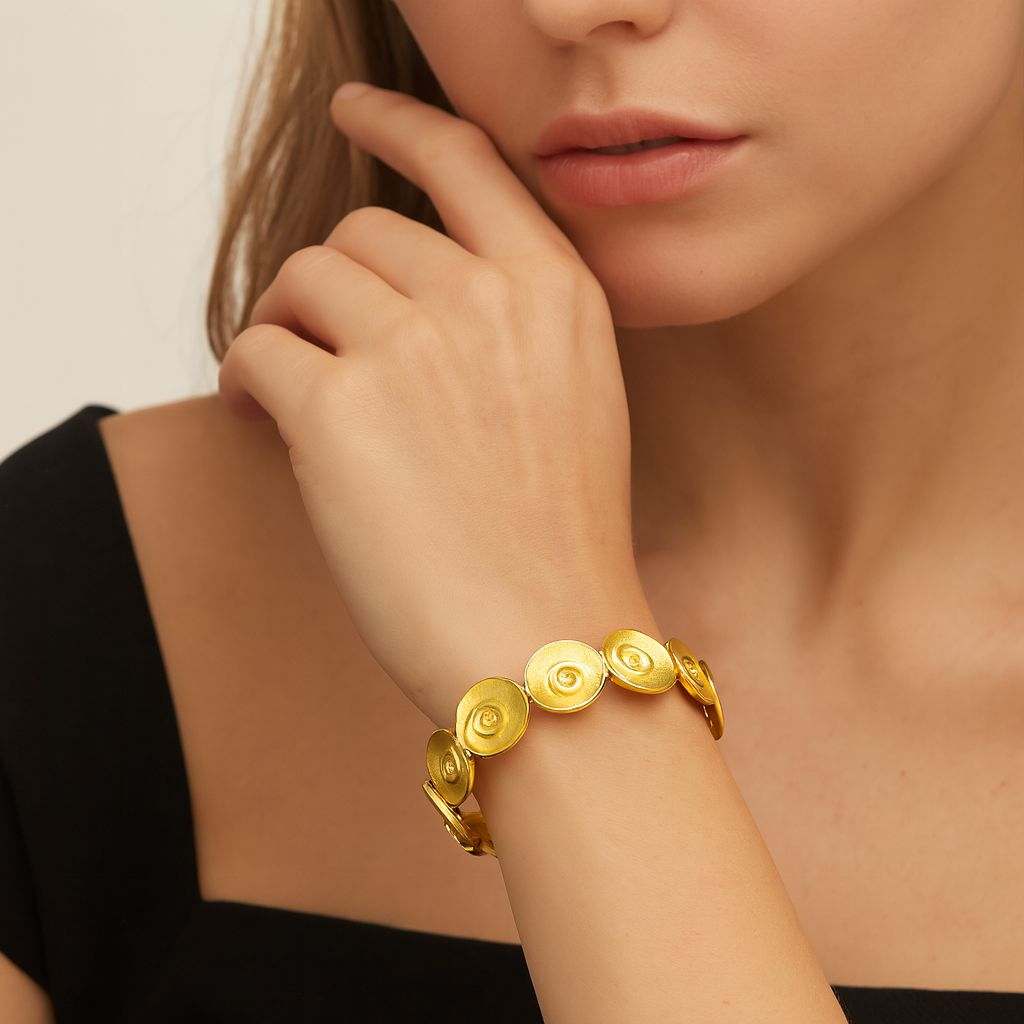 Spiral Swirl KC gold plated bracelet with artistic textured circular discs on woman's wrist