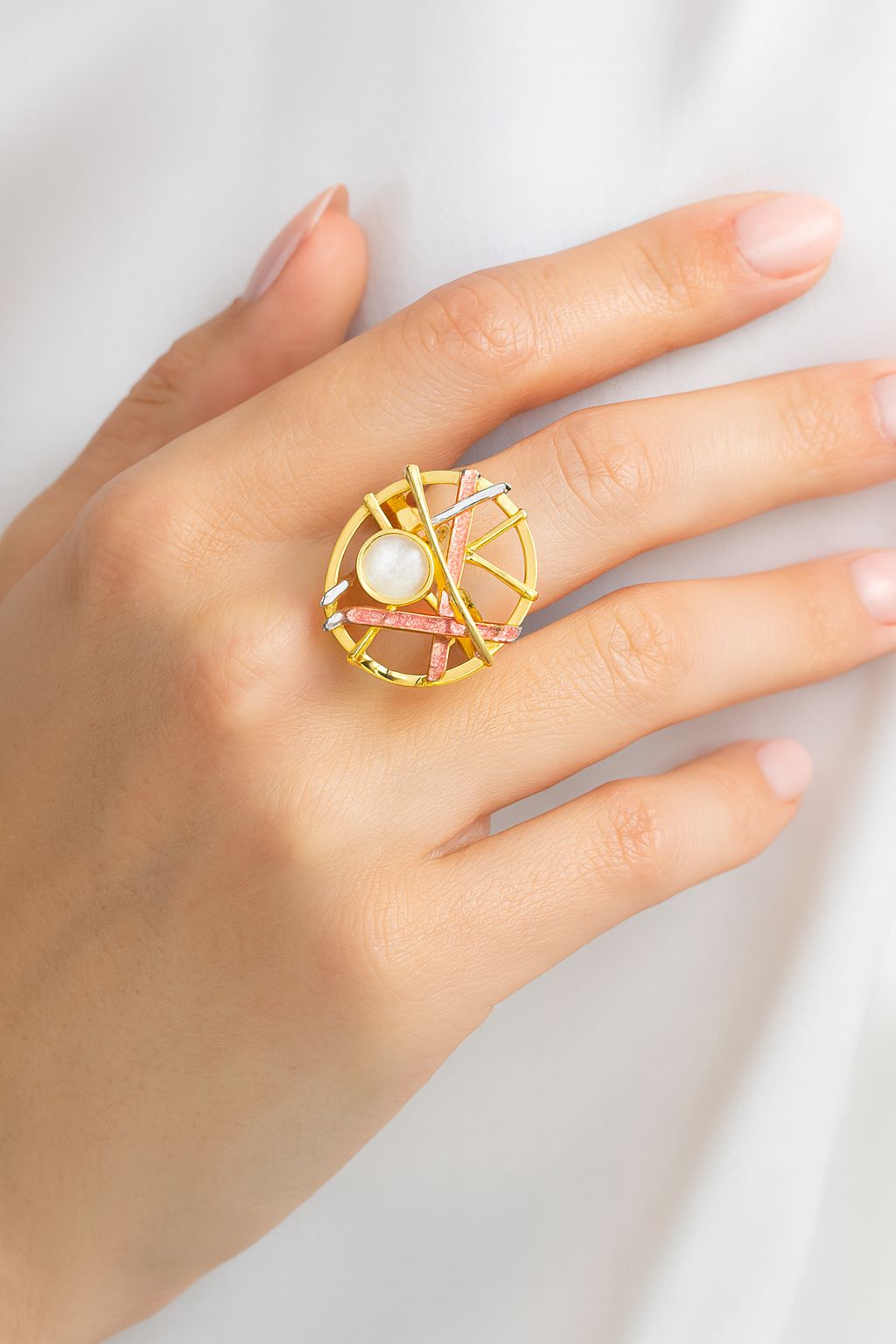 “Model wearing abstract art statement ring in coral and gold tones